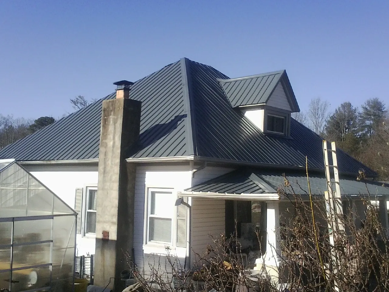 Dark blue standing seam metal roof on a white farmhouse with dormer — Slate & Tile Roof Repair by Roofing Brothers in Hopewell
