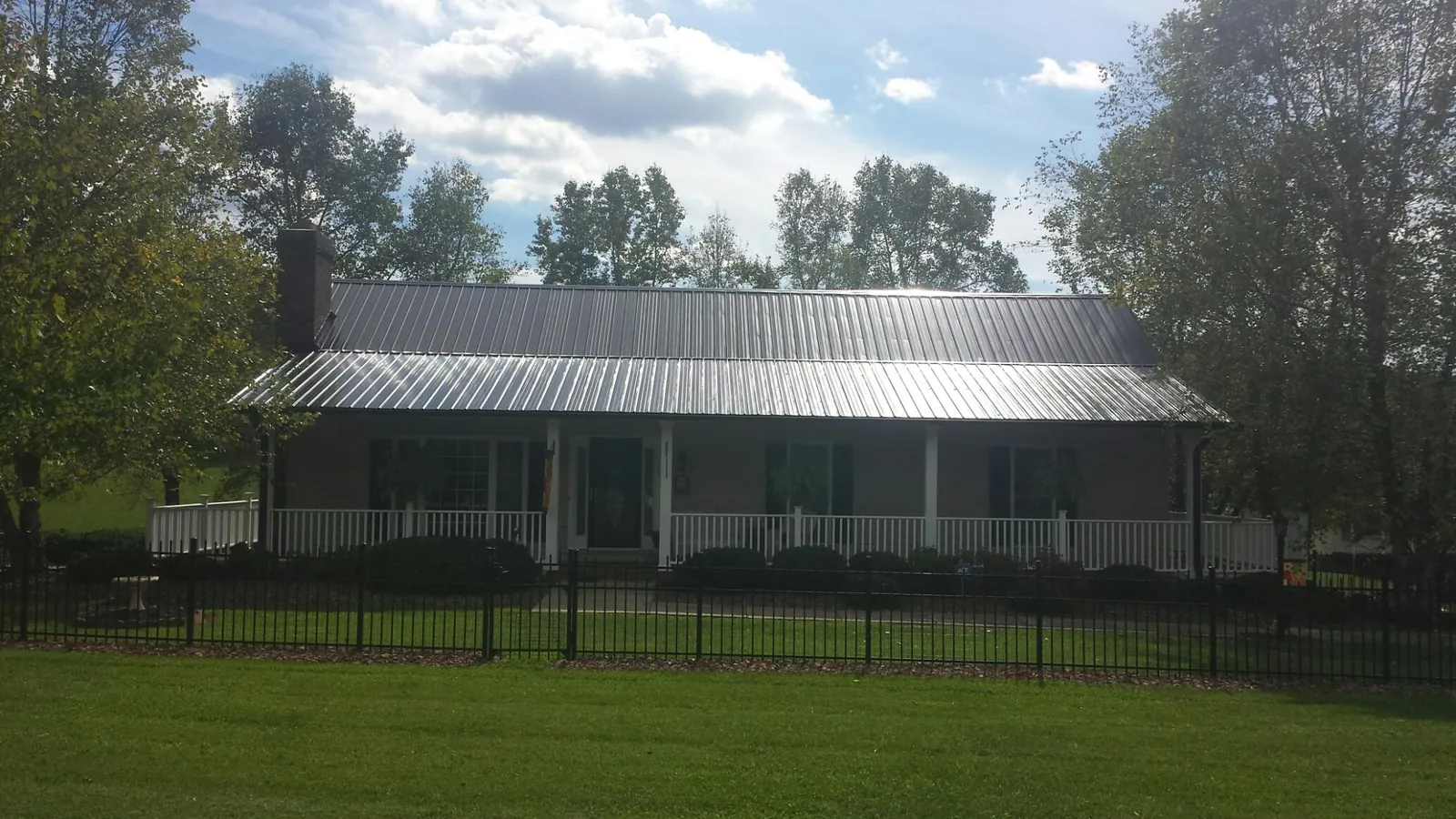 Gray metal roof on a brick ranch with a full width front porch — Gutter Guard Installation work by our crew in Hopewell
