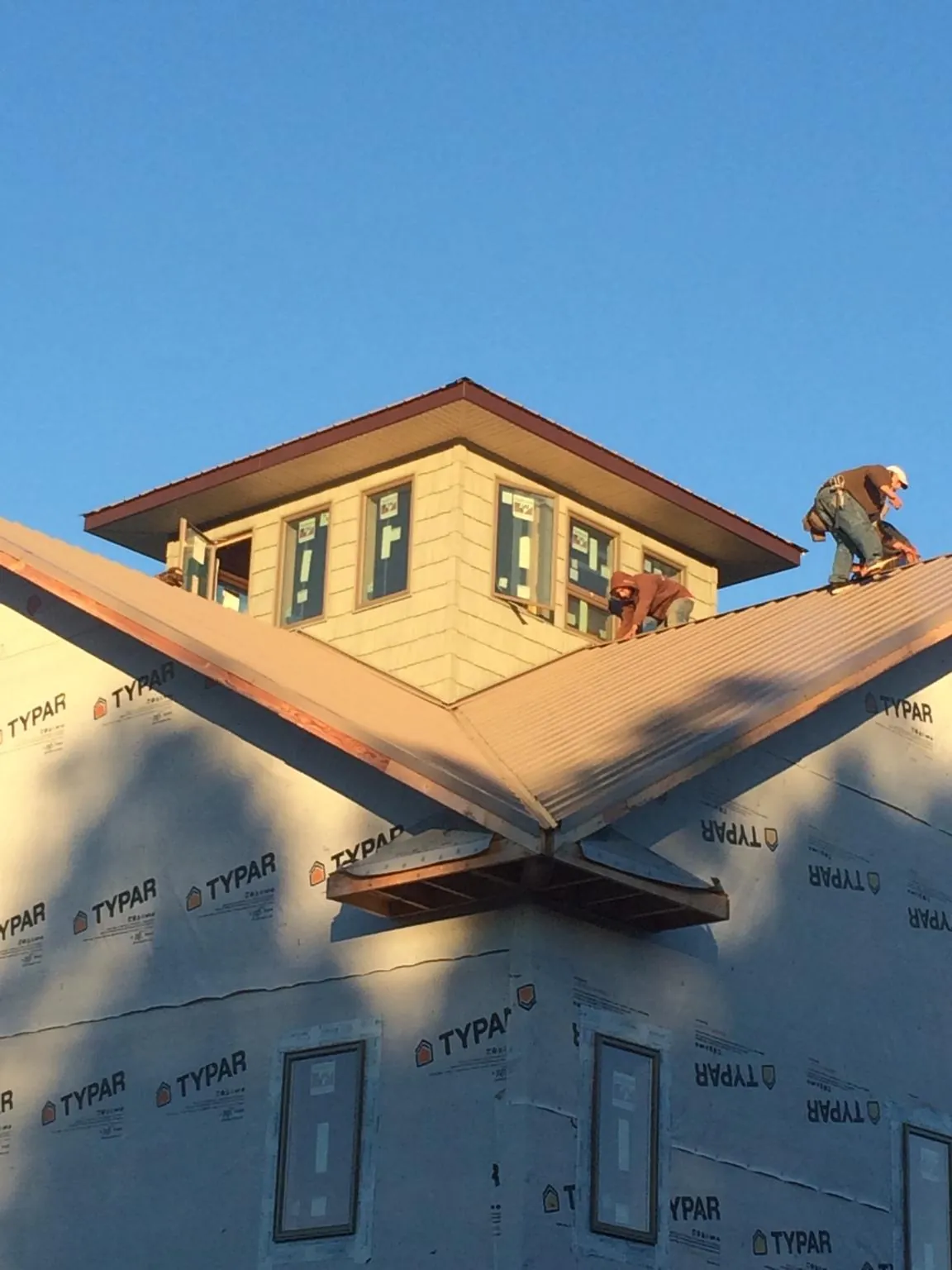 Roofers working around a rooftop cupola on a new metal roof at sunset — Roof Waterproofing in Hopewell by Roofing Brothers